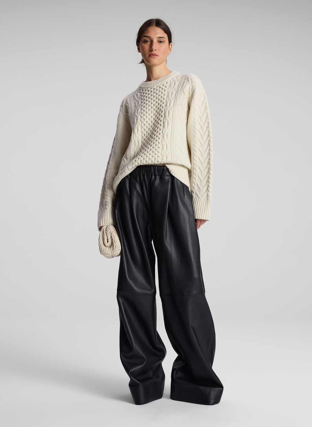 woman wearing cream cable knit sweater and black leather pants