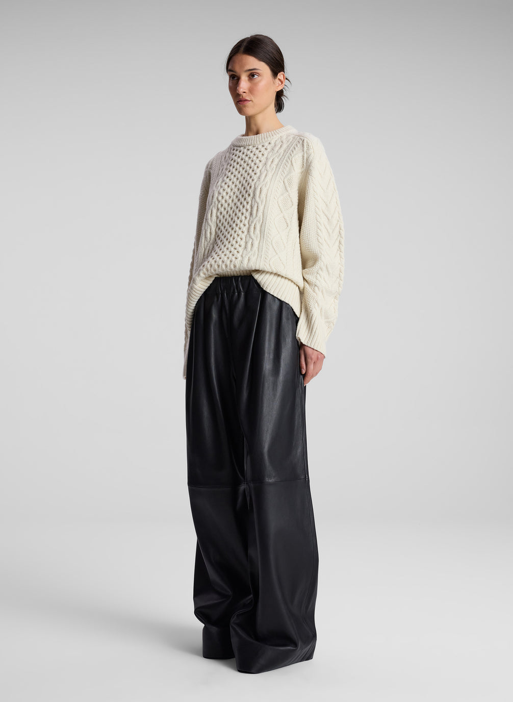 woman wearing cream cable knit sweater and black leather pants