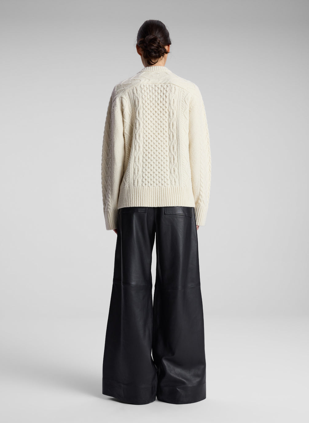 woman wearing cream cable knit sweater and black leather pants