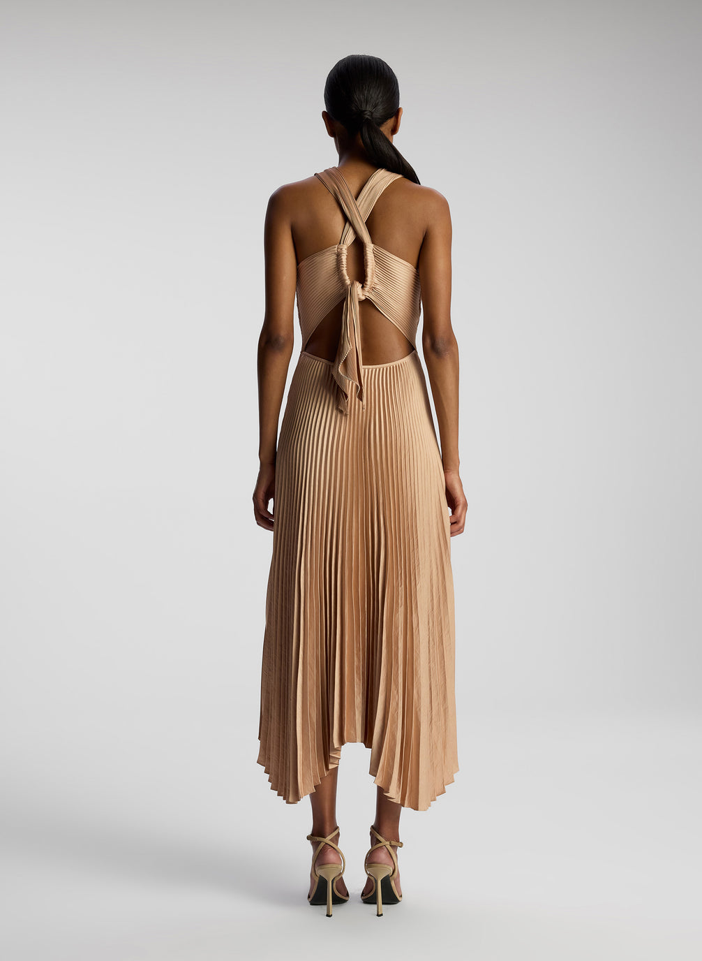 back view of woman wearing blush colored pleated midi dress
