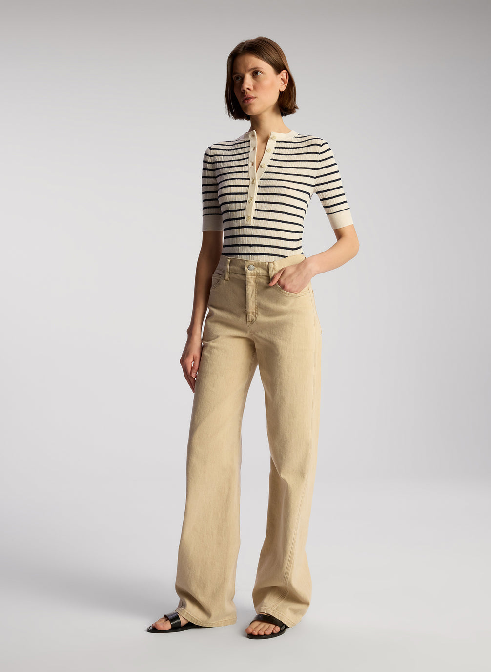 side view of woman wearing navy blue and white striped shirt and tan pants