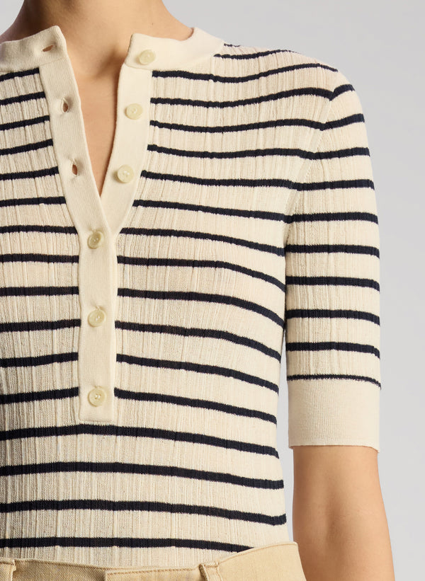 detail view of woman wearing navy blue and white striped shirt and tan pants