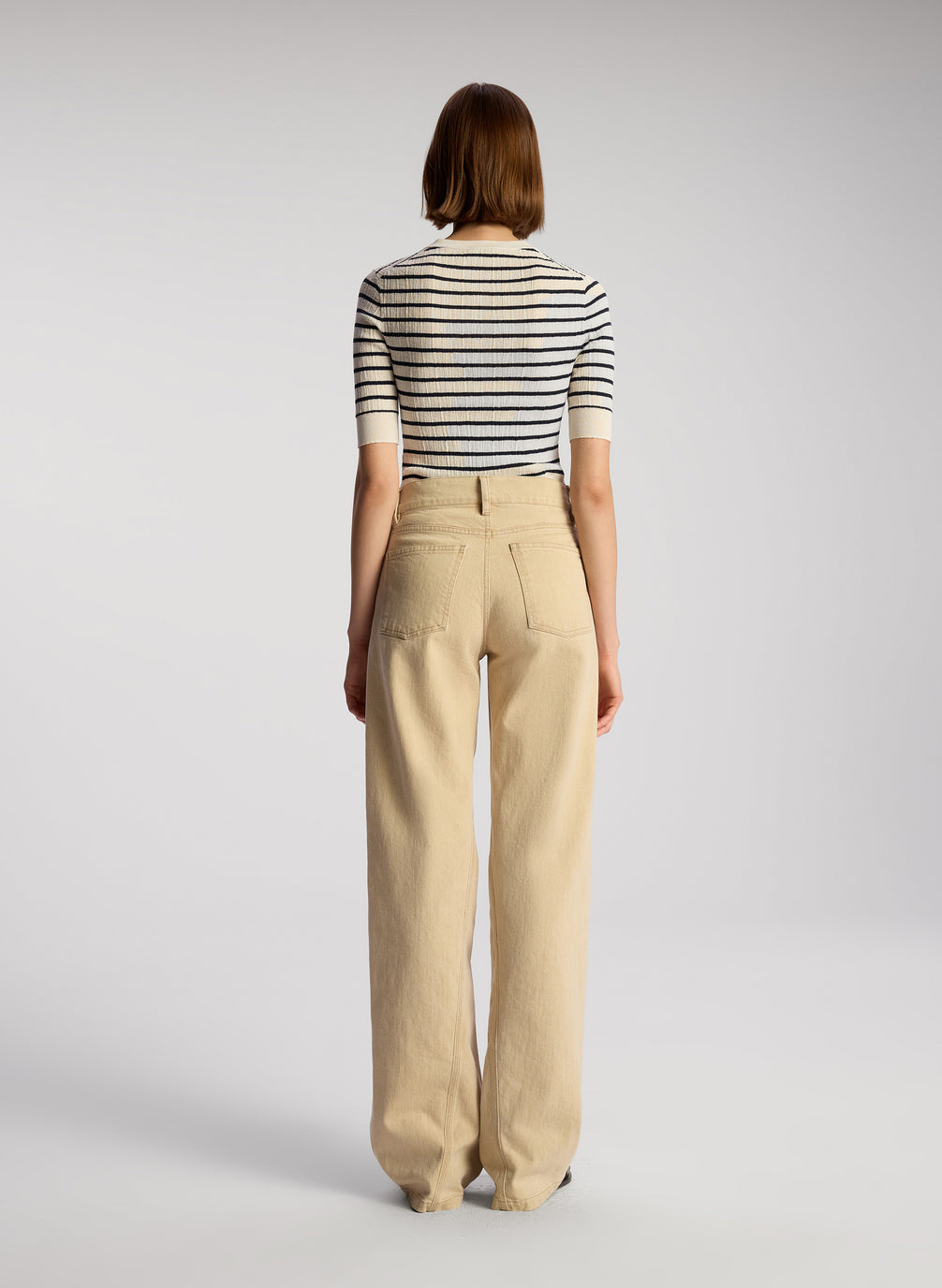 back view of woman wearing navy blue and white striped shirt and tan pants