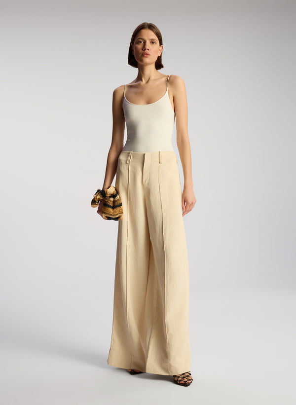 front view of woman wearing off white bodysuit and beige wide leg pants