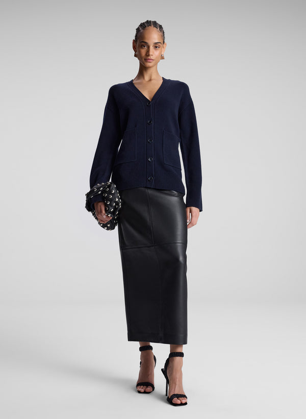 woman wearing navy blue cardigan and back leather midi skirt