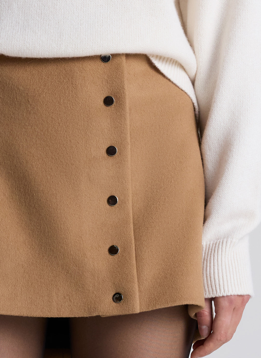 woman wearing white turtleneck sweater and camel button front mini skirt