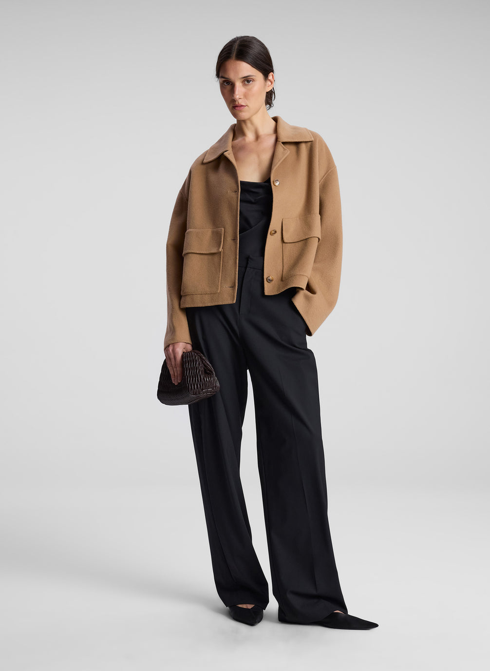 woman wearing camel jacket black top and black pants