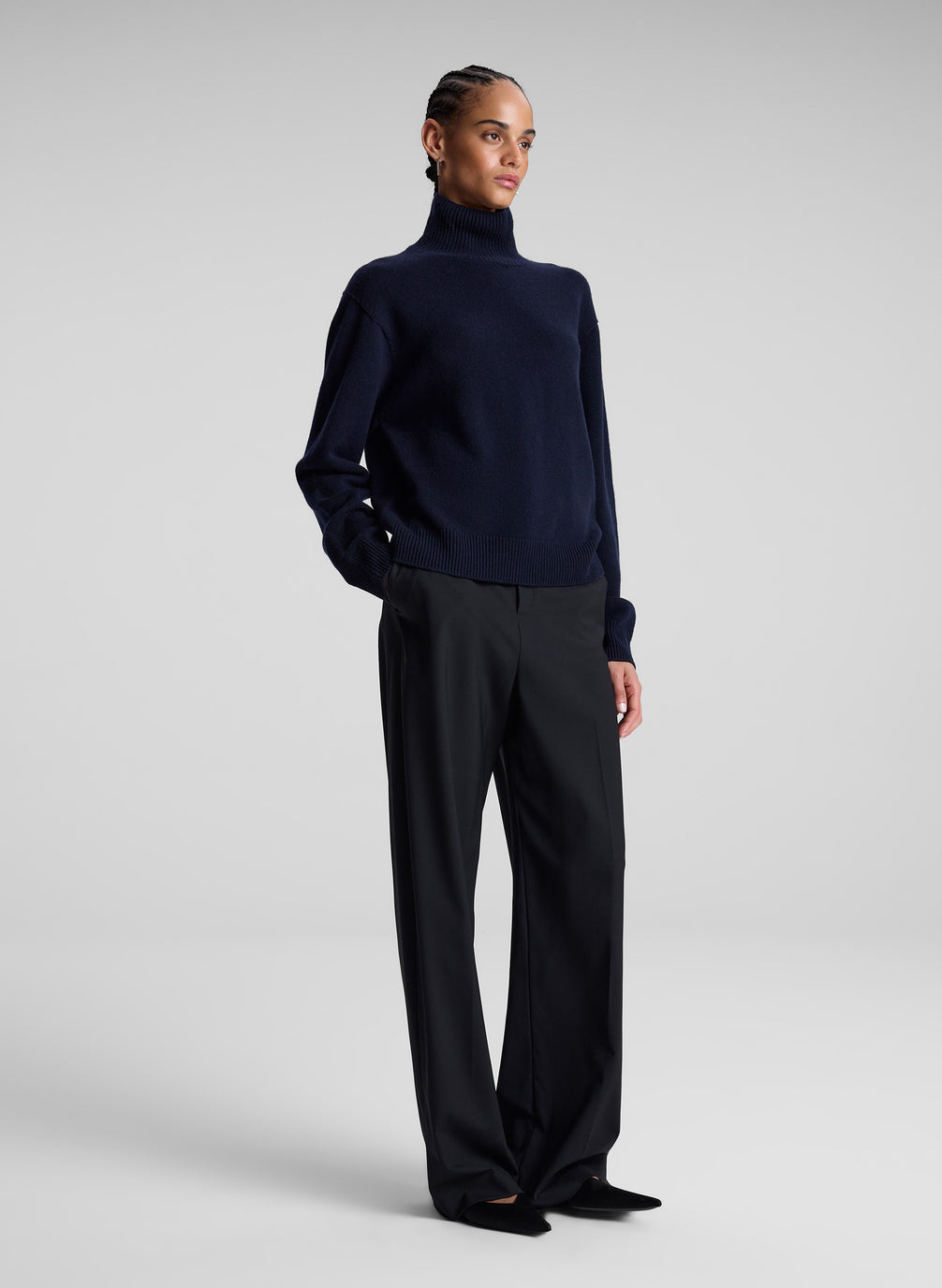 woman wearing navy turtleneck sweater and grey pants