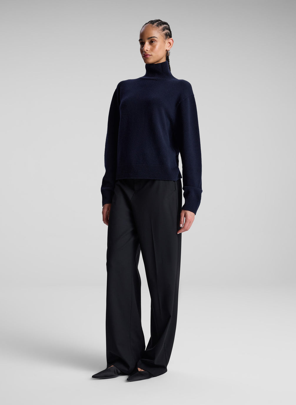 woman wearing navy turtleneck sweater and grey pants