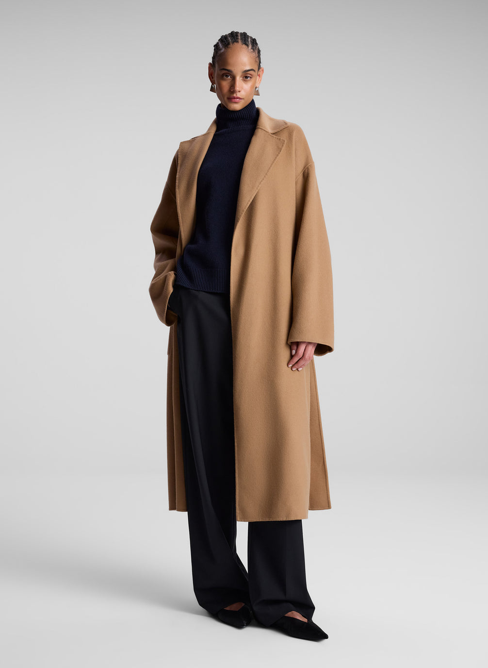 woman wearing camel color wool coat, black turtleneck, and black pants