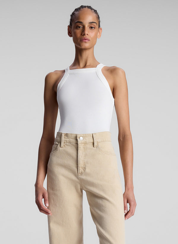 front view of woman wearing white tank top and tan pants