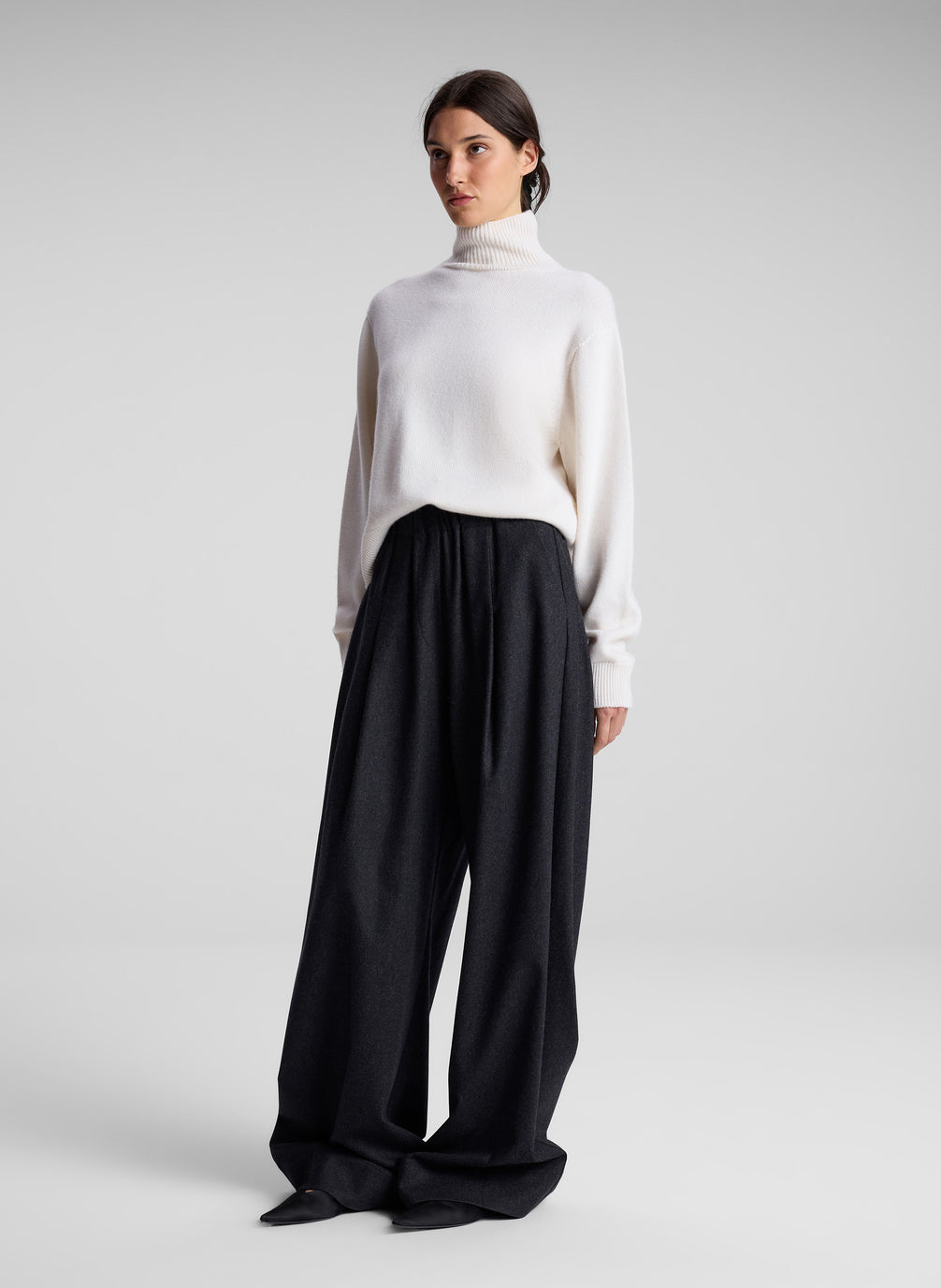 woman wearing white turtleneck sweater and charcoal grey wide leg pants