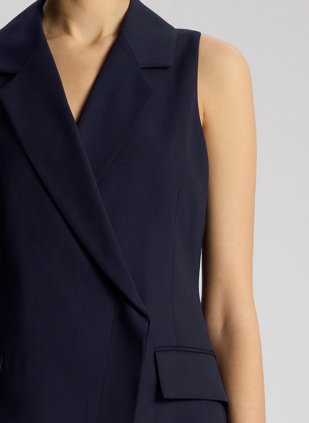 detail view of woman wearing navy blue sleeveless blazer mini dress