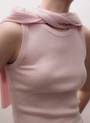 Person wearing a light pink sleeveless top with a pink top over shoulders against a neutral background