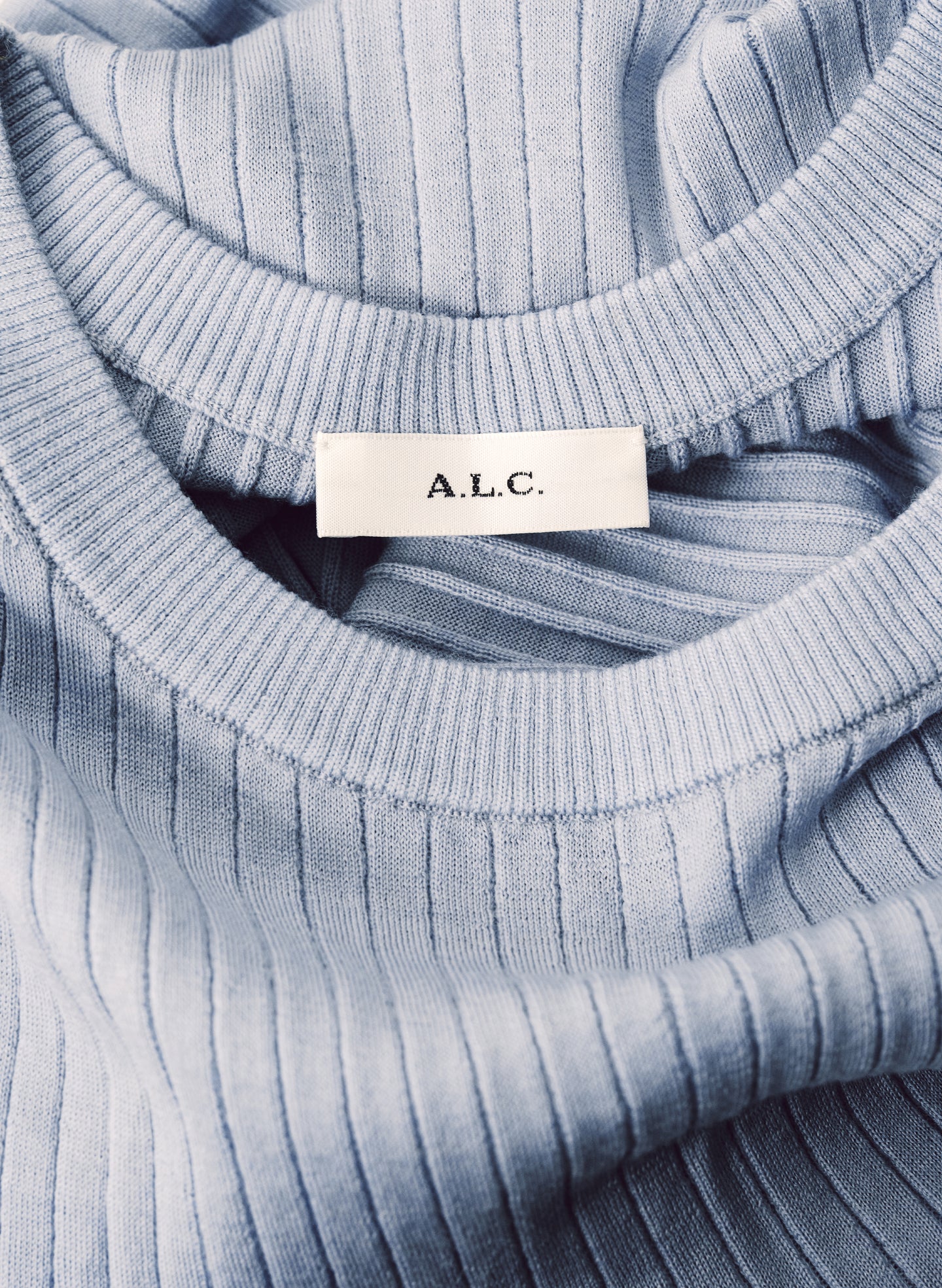 Close-up of a ribbed knit sweater with 'A.L.C.' label