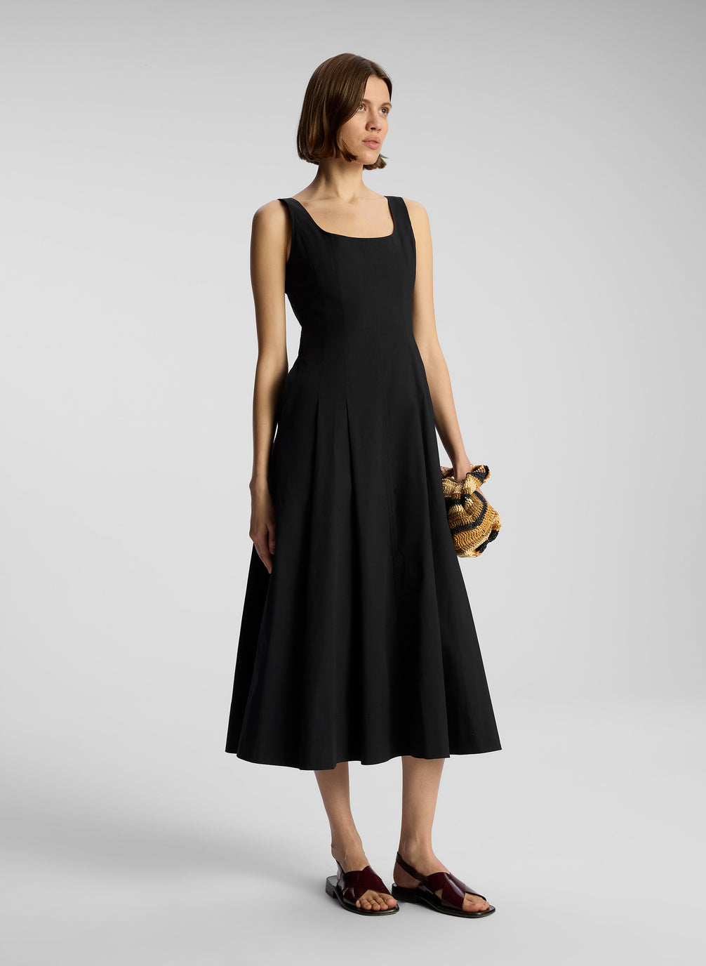 side view of woman wearing black sleeveless midi dress