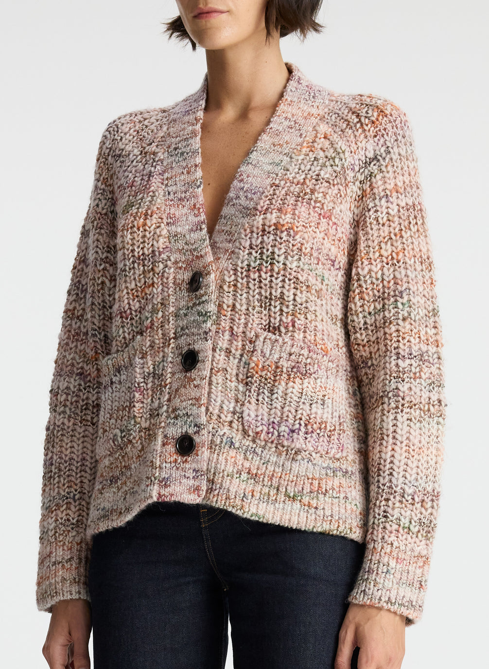 detail view of woman wearing multicolor cream, brown, purple, and green long sleeve knit cardigan with v neck, 3 front buttons, and two front pockets