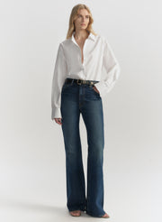 Woman wearing a white blouse and blue jeans on a plain background
