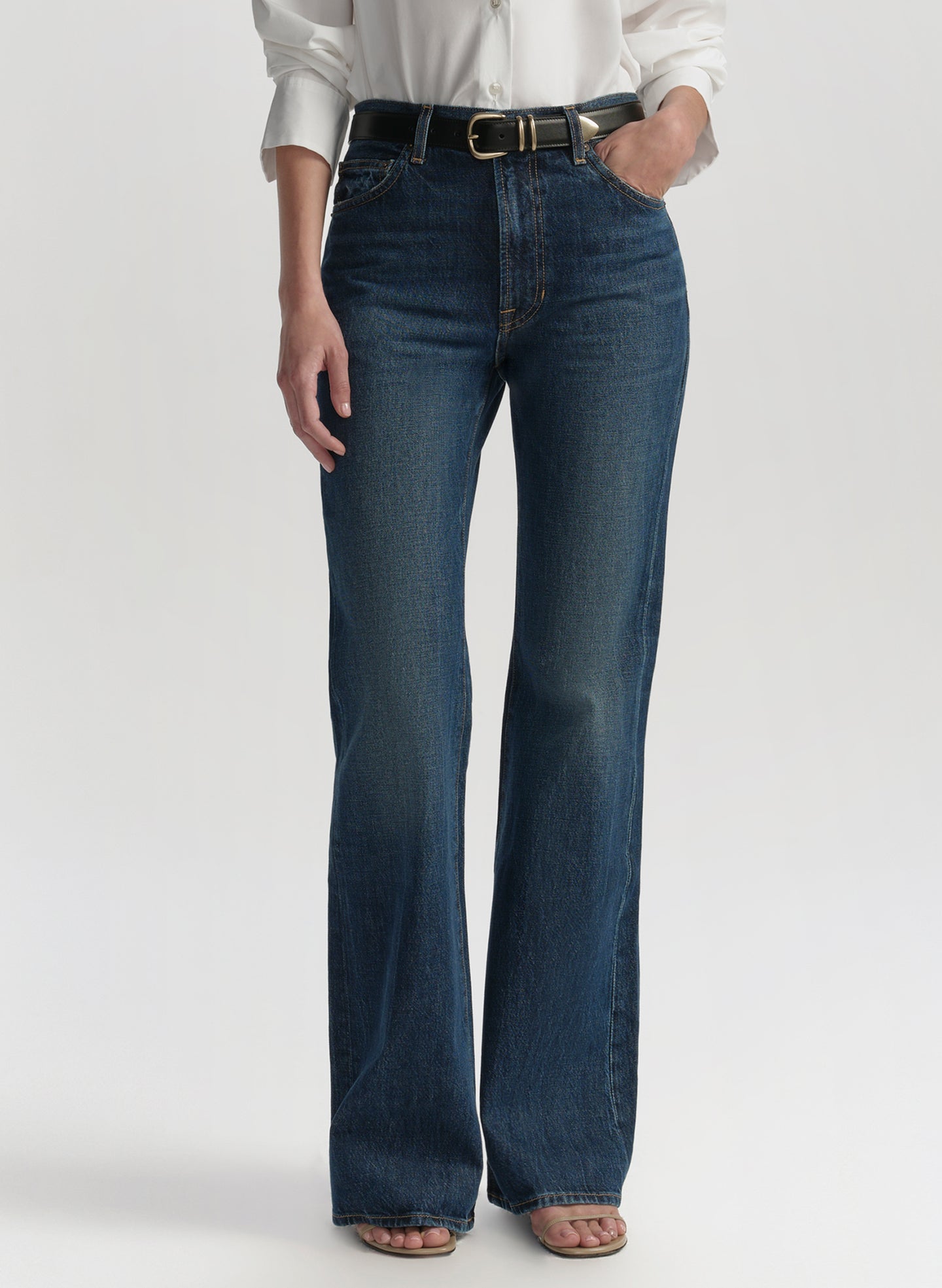 Woman wearing a white blouse and blue jeans on a plain background