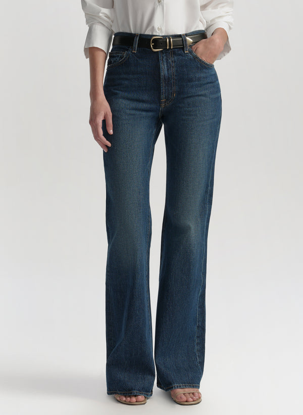 Woman wearing a white blouse and blue jeans on a plain background