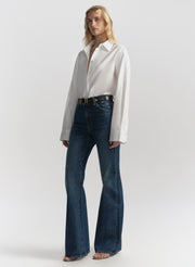 Woman wearing a white blouse and blue jeans on a plain background