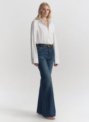 Woman wearing a white blouse and blue jeans on a plain background