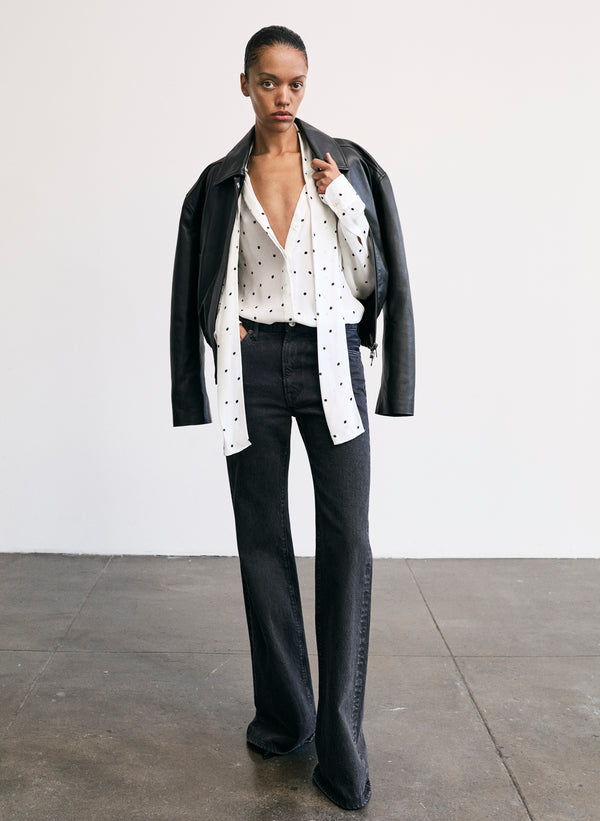 woman wearing polka dot top and black denim jeans