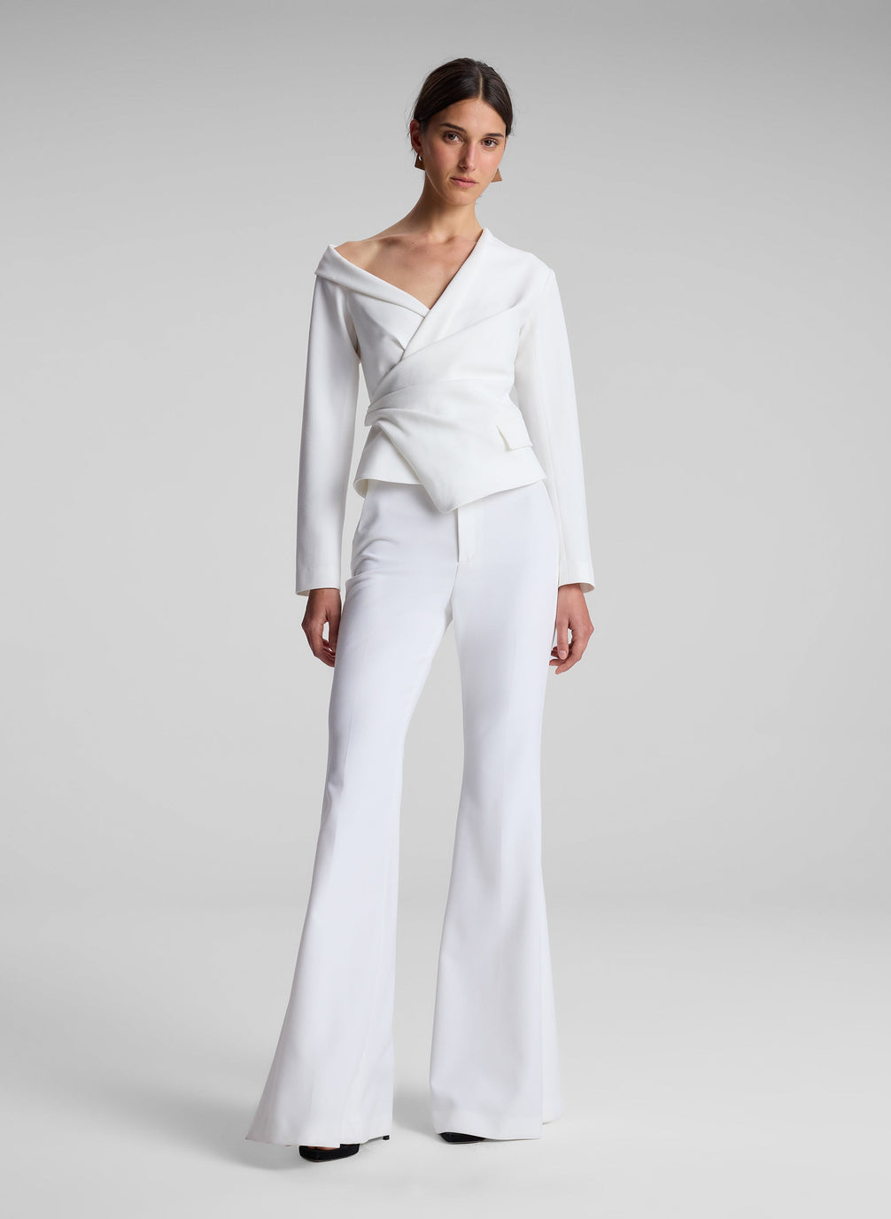 woman wearing white asymmetric top and white flared pants