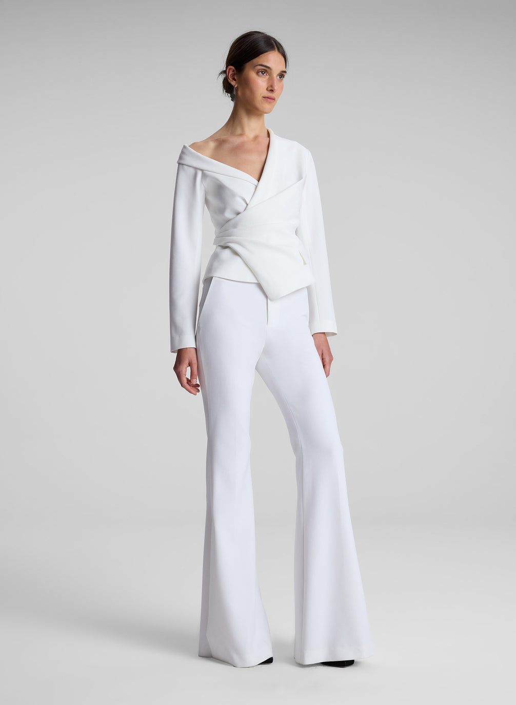 woman wearing white asymmetric top and white flared pants