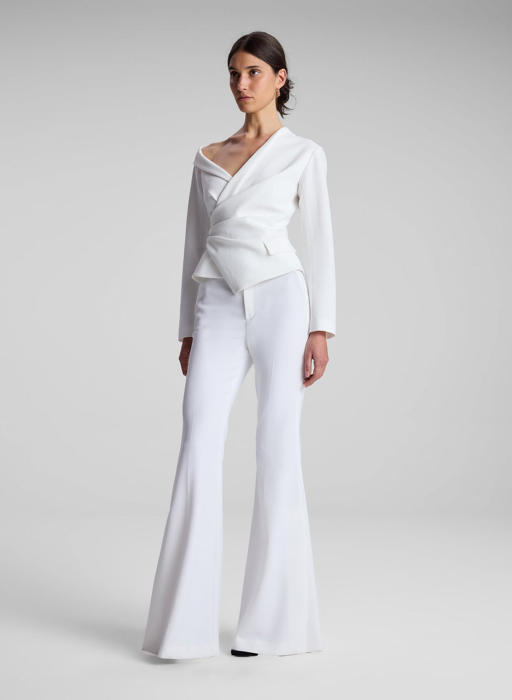 woman wearing white asymmetric top and white flared pants