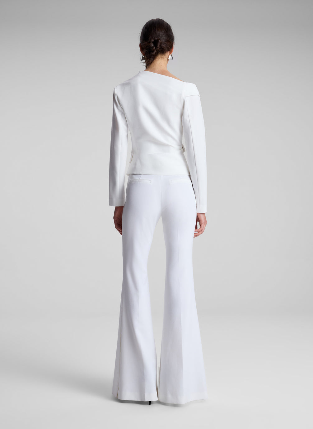 woman wearing white asymmetric top and white flared pants