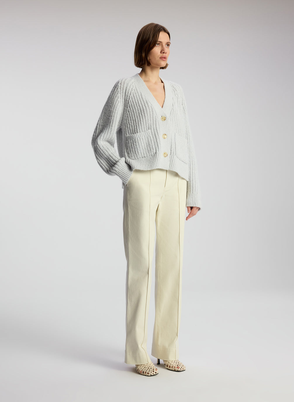 side view of woman wearing beige pants and blue cardigan