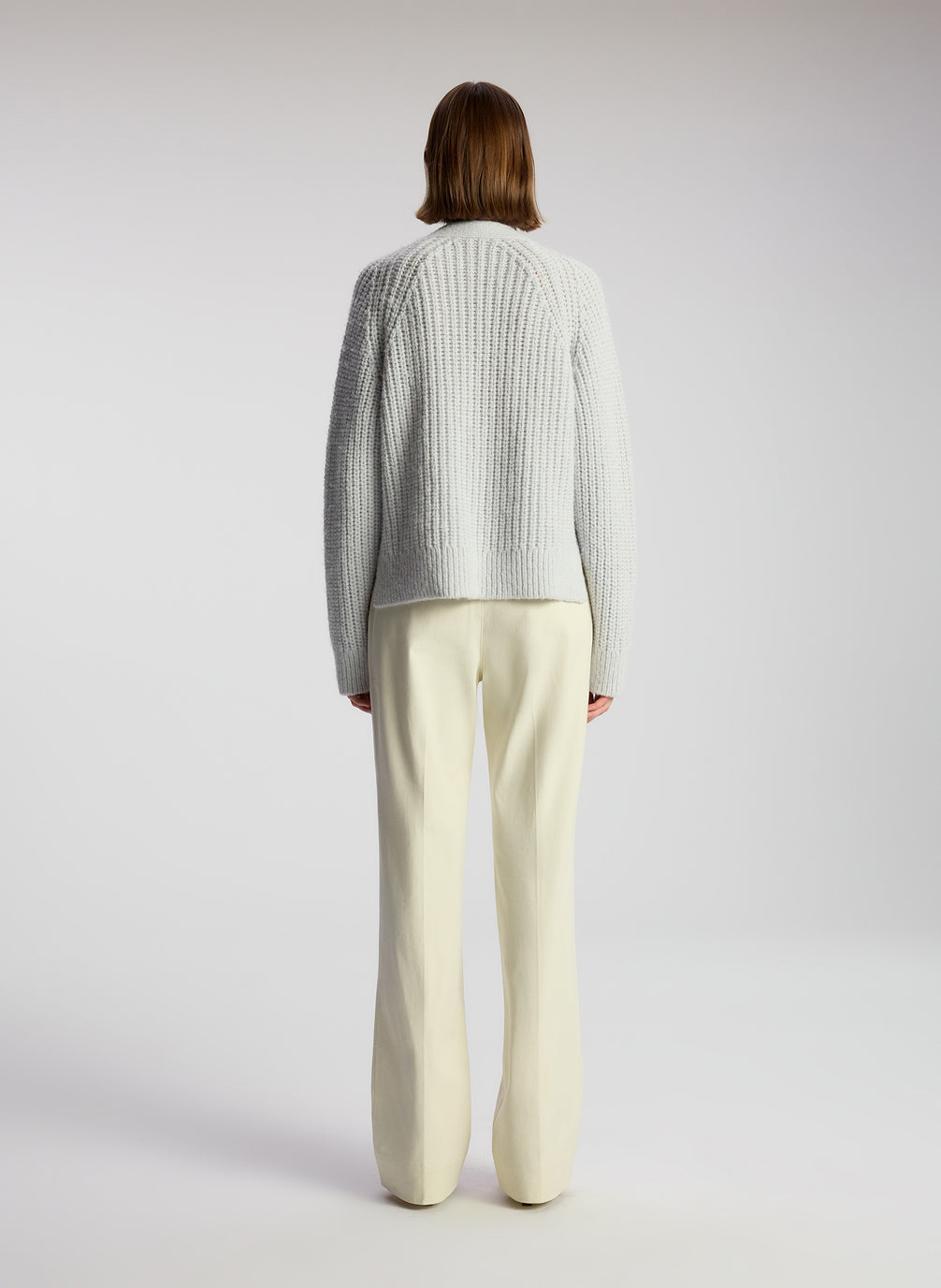 back view of woman wearing beige pants and blue cardigan