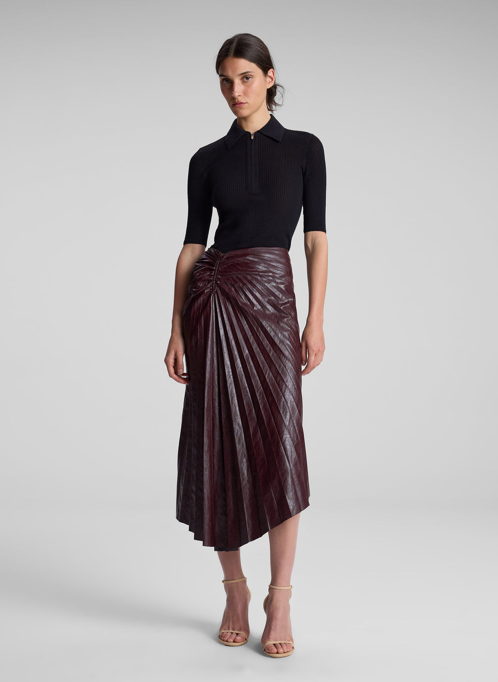 woman wearing black top and burgundy pleated skirt