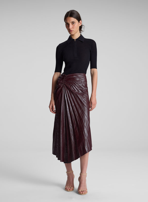 woman wearing black top and burgundy pleated skirt