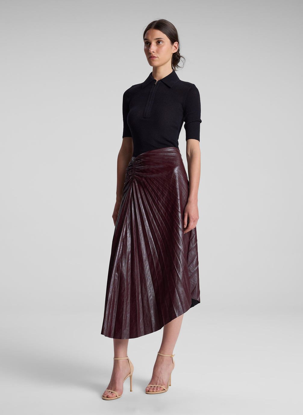 woman wearing black top and burgundy pleated skirt