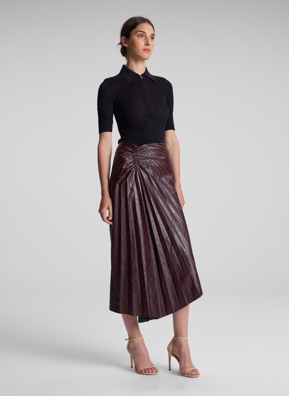 woman wearing black top and burgundy pleated skirt