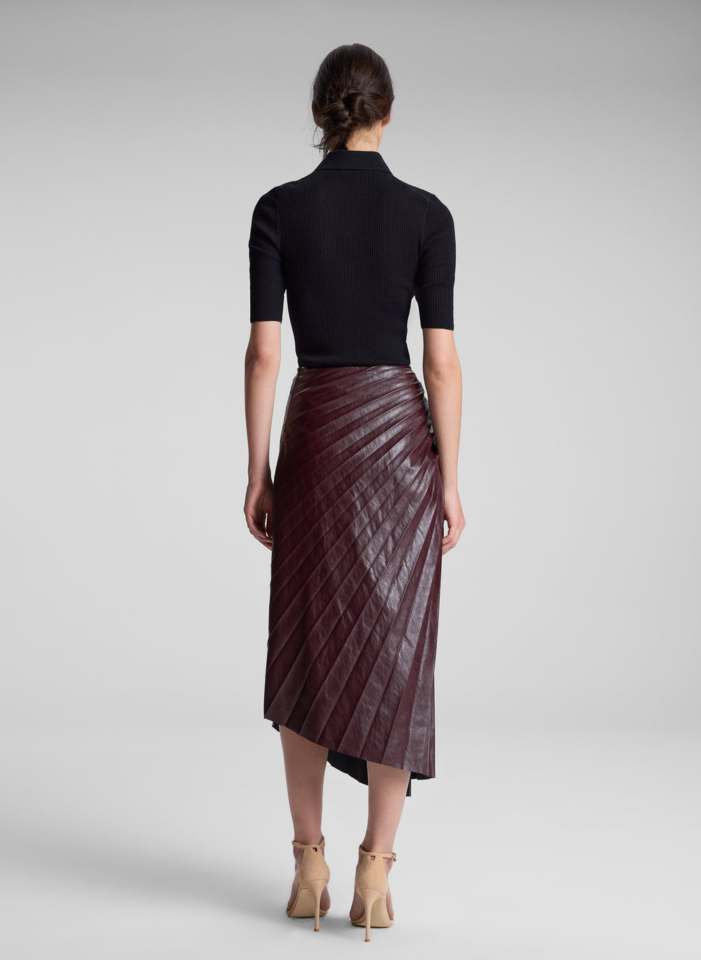 woman wearing black top and burgundy pleated skirt