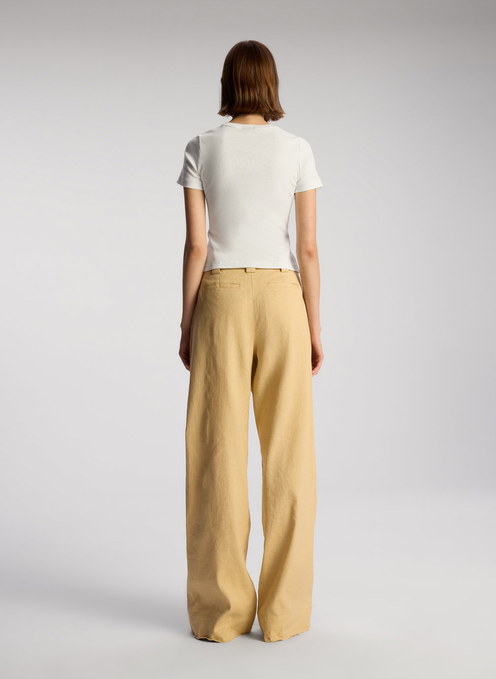 back view of woman wearing white tshirt and beige wide leg pants