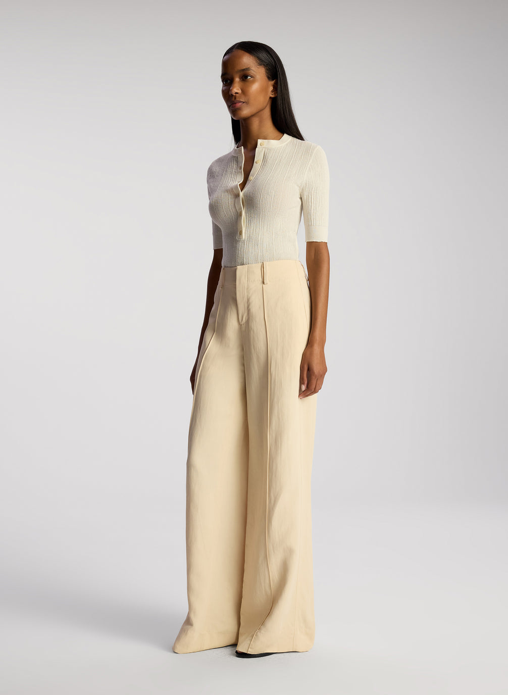 side view of woman wearing white top and cream wide leg pants