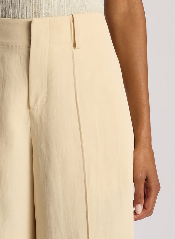 detail view of woman wearing white top and cream wide leg pants