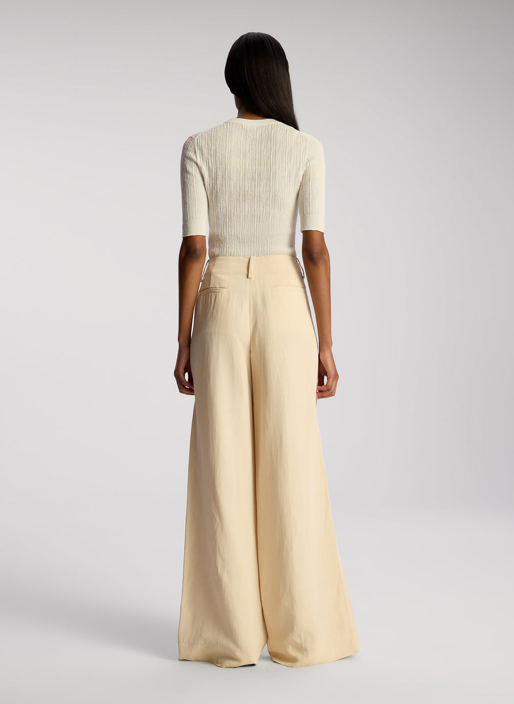 back view of woman wearing white top and cream wide leg pants