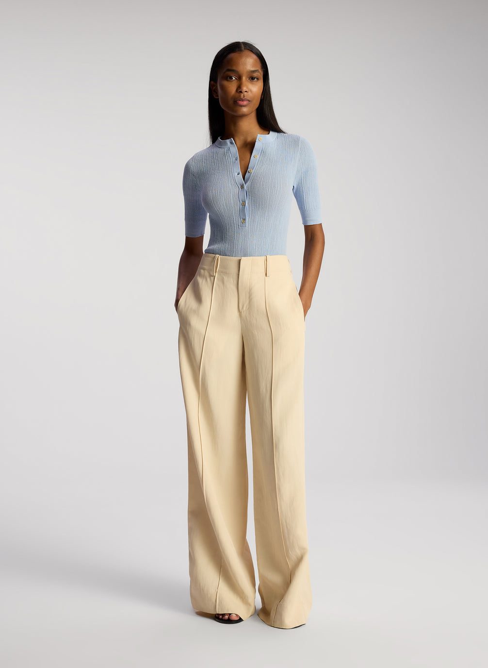 front view of woman wearing blue top and cream pants