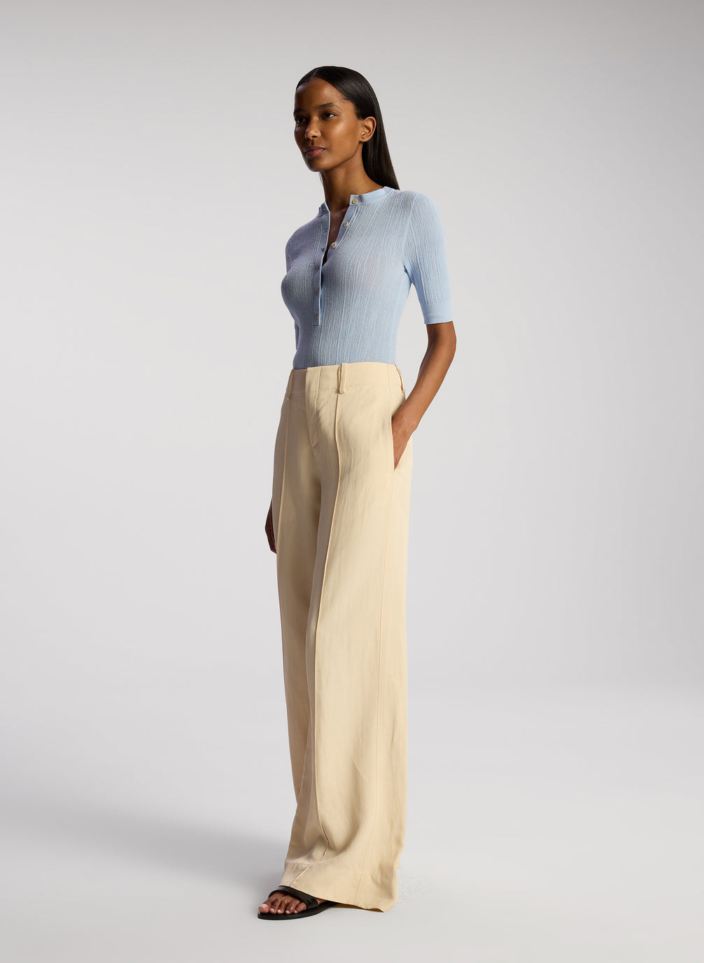 side view of woman wearing blue top and cream pants