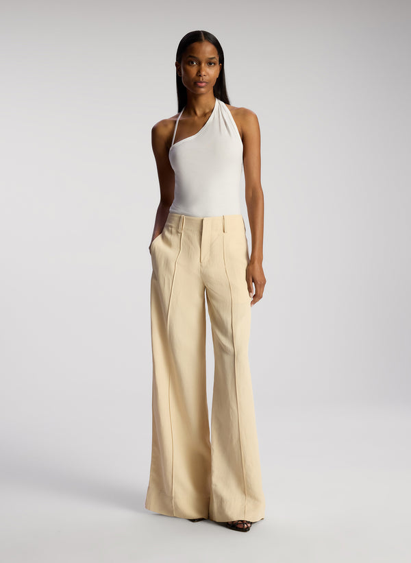 front view of woman wearing white asymmetric tank and cream wide leg pants 