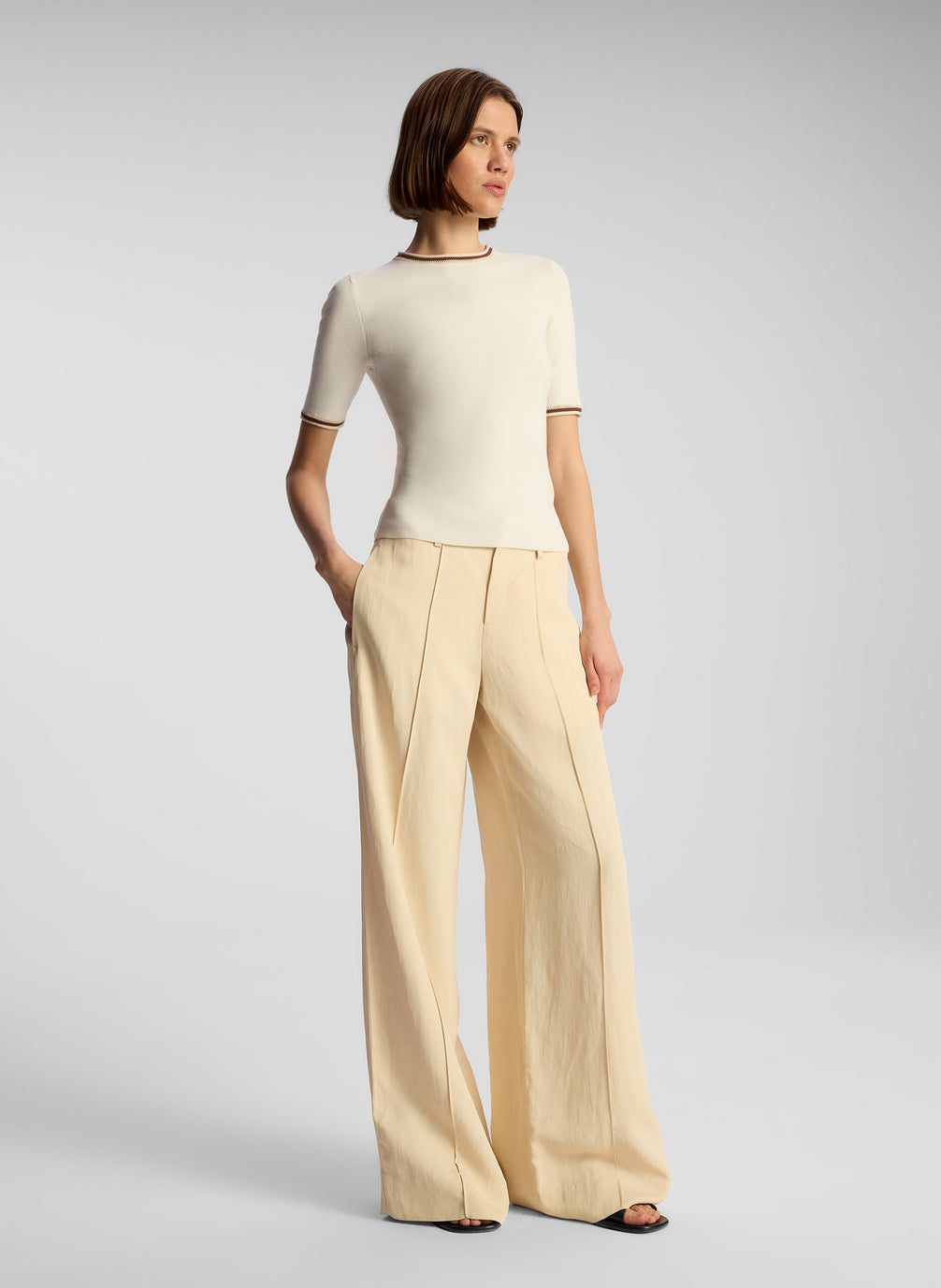 side view of woman wearing white top and beige pants