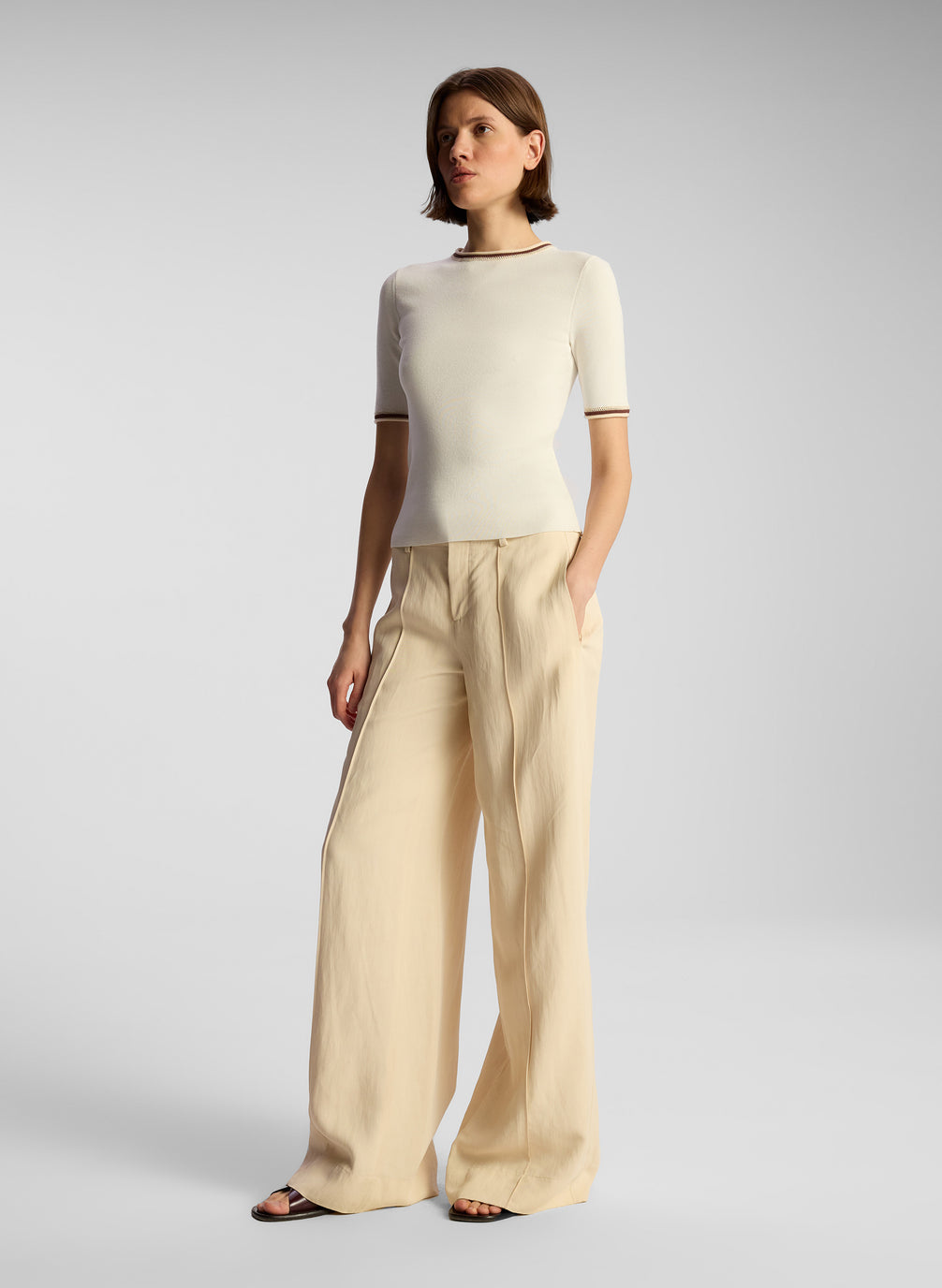 side  view of woman wearing white top and beige pants