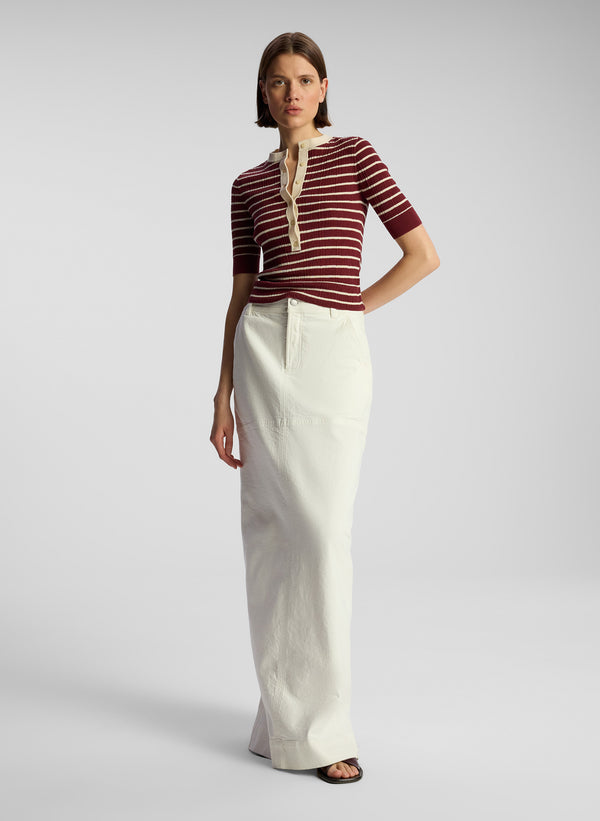 front view of woman wearing burgundy striped top and white maxi skirt