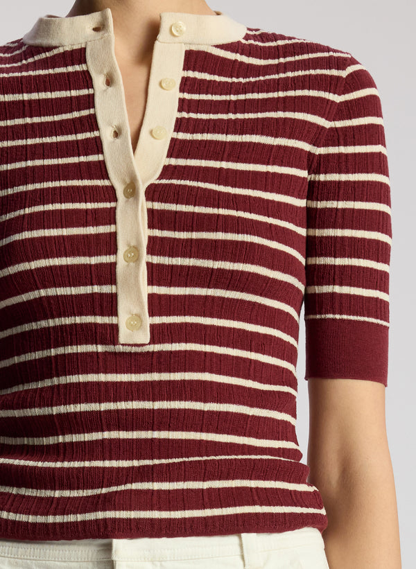 detail view of woman wearing burgundy striped top and white maxi skirt