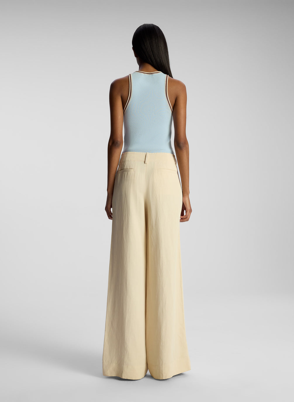 back  view of woman wearing light blue tank top and beige pants